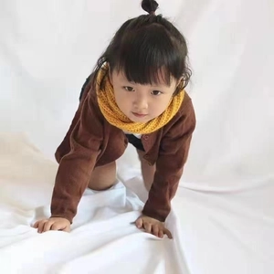 Close-up of a child wearing a warm yellow knit scarf with a brown cardigan sweater