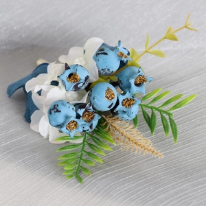 Forest-style wedding boutonniere with blue berries, white petals and green leaves