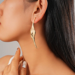 Close-up of model wearing gold irregular curved geometric earrings with a modern design