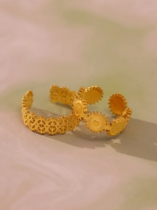 Dettaglio di due anelli geometrici vintage dorati con motivi a sole in stile boho