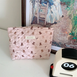 Detail of pink quilted cosmetic bag with cute animal prints and woven brand label