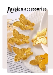 Macro shot of double butterfly stud earrings with brushed gold texture on a ceramic plate