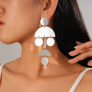 Dettaglio di orecchini pendenti geometrici in argento indossati da una modella elegante