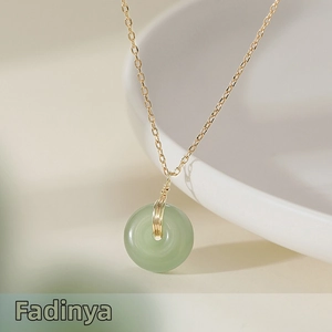 Close-up of green jade pendant with gold wire wrap on a fine gold cross chain