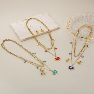Detailed view of layered gold evil eye necklaces and matching heart stud earrings set