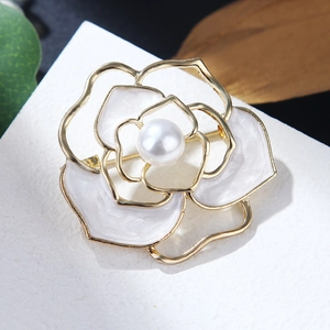 Detailed close-up of a golden camellia brooch with white enamel petals and pearl center