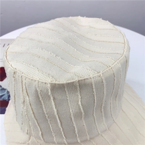 Détail d'un chapeau bob rayé beige en coton et lin avec des bords effilochés élégants