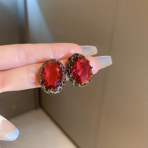 Detailed view of vintage oval red gemstone earrings with ornate black metal filigree