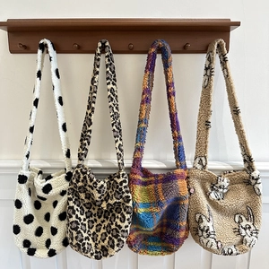 Fuzzy plush tote bags in leopard, polka dot and plaid patterns on wooden hooks