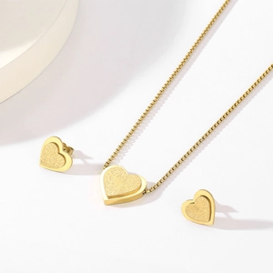 Close-up of golden heart jewelry set featuring matte and polished star-motif textures