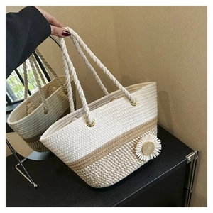 Close-up of woven tote bag featuring a white daisy flower detail and two-tone stitching