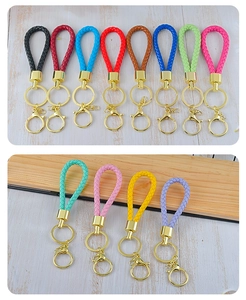 Close-up of multicolored braided leather keychains with golden metal rings on wood