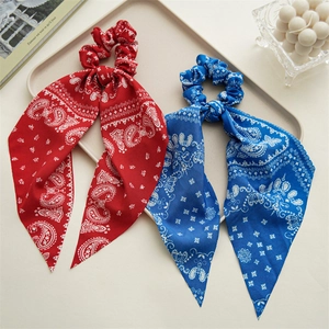 Detail showing red and blue paisley print hair scrunchies with long streamers on a tray