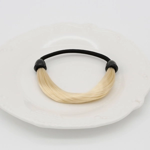 Détail de l'extension en cheveux synthétiques dorés sur un élastique noir robuste