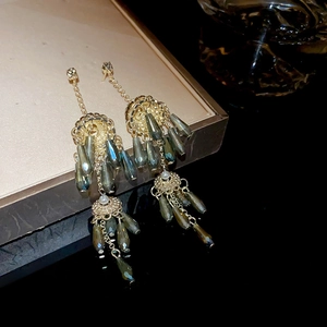 Detail of vintage long tassel earrings with grey-blue teardrop beads on a gold tray