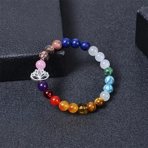 Natural chakra stone beaded bracelet with silver lotus flower pendant on dark background
