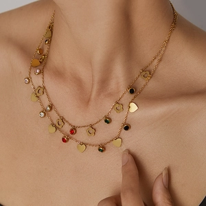 Close-up of double-layered gold necklace with colorful zircon pendants and heart charms