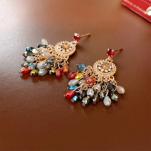 Detail of vintage gold earrings featuring rhinestones and colorful gemstone tassels