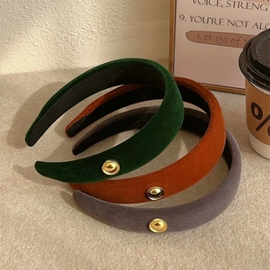 Three velvet headbands in green, brown and grey with golden logo coin accents