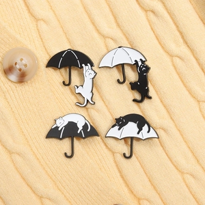 Détail de quatre épingles en pin's émaillés chat noir et blanc sur un fond en tricot jaune