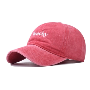 Dettaglio del ricamo della lettera Peachy su un cappello di cotone rosso lavato