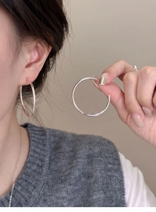 Close-up of elegant silver round hoop earrings worn by a model in a minimalist style