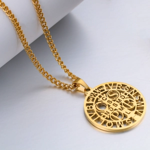 Golden Saint Benedict medal necklace in stainless steel on a white reflective background