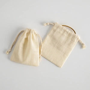 Detail of off-white cotton linen drawstring pouch with a gold ring inside