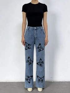 Détail d'un jean bleu clair à jambe droite avec des imprimés papillon noirs sur denim taille haute