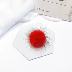 Soft red faux mink fur pom-pom accessory on a white tile for DIY jewelry and hair crafts