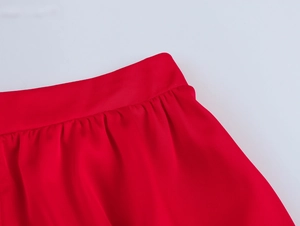 Détail de la texture du tissu rouge lisse et de la taille volantée sur le short