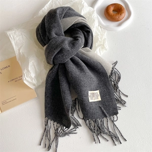Detail view of charcoal and light grey reversible scarf with tassels and fabric label