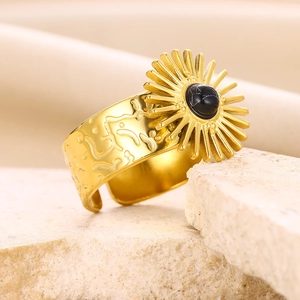 Detailed close-up of a gold sunflower ring with black natural stone and textured band