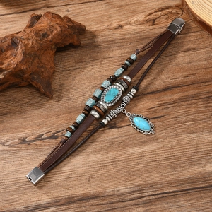 Detail of vintage braided leather bracelet with turquoise stones and wooden beads on wood
