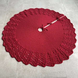 Close-up of deep red knitted Christmas tree skirt with hollowed-out wave edges