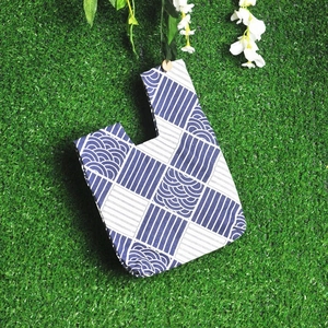 Japanese style linen wrist bag with blue wave patterns on a green grass background