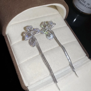 Close-up of flower tassel earrings with zircons and pearls on brown velvet jewelry box