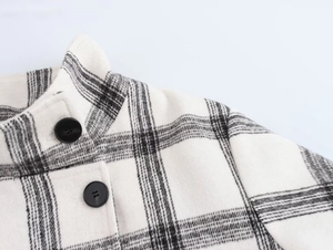 Macro detail of high stand collar and black resin buttons on plaid jacket