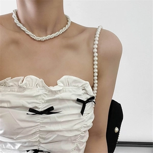 Detail of multi-layer pearl necklace with a black bow accent on an elegant collarbone
