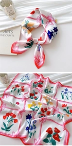 Detail of elegant floral silk scarf with red border and bow pattern on white satin