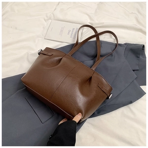 Detail of soft brown leather tote bag with pleated texture and side metal buckle design