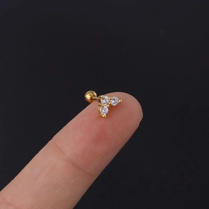 Macro view of a tiny gold screw-back stud earring with three clear round-cut zircons