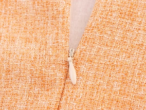 Détail de la texture du tissu en tweed orange et de la fermeture éclair invisible