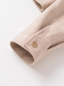 Macro view of beige tweed jacket cuff with a polished gold round button detail