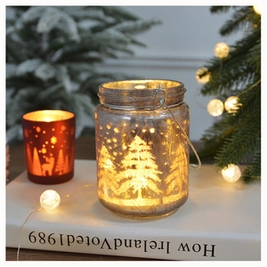 Close-up of frosted glass lantern with Christmas tree silhouette and warm LED glow