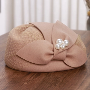 Detail of elegant wool felt pillbox hat with mesh veil, bow and pearl accents