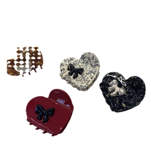 Acetate heart hair claws with bow details in burgundy, marble, and amber colors
