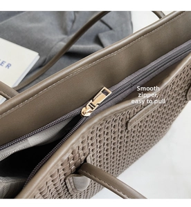 Macro detail of the smooth gold zipper closure on this woven brown tote bag