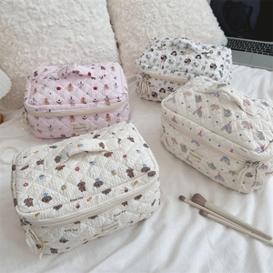 Detailed group shot of quilted cosmetic bags with cute animal patterns on a cozy bed