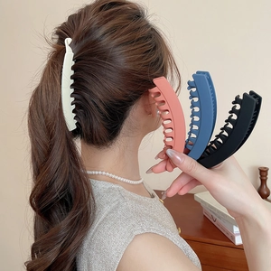 Gros plan d'une pince banane en acrylique mat pour femme dans une coiffure élégante